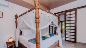 A four-poster bed with a canopy, a bedside table with a lamp, and a view of the outside through a wooden door. - 28 Degrees Lembongan (Lembongan Island)