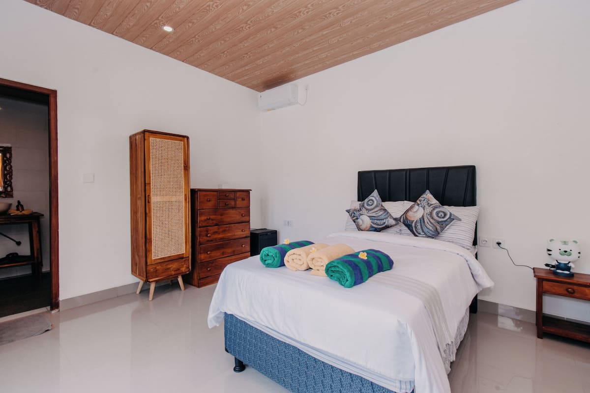 Un dormitorio con cama, armario de madera y mesita de noche.