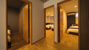 Una camera d'albergo con pavimento in legno, un letto con biancheria bianca e un condizionatore d'aria a soffitto.
