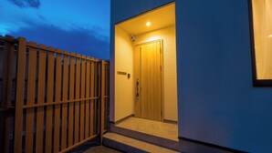 Ingresso di un edificio moderno con una porta in legno e una scalinata adiacente.