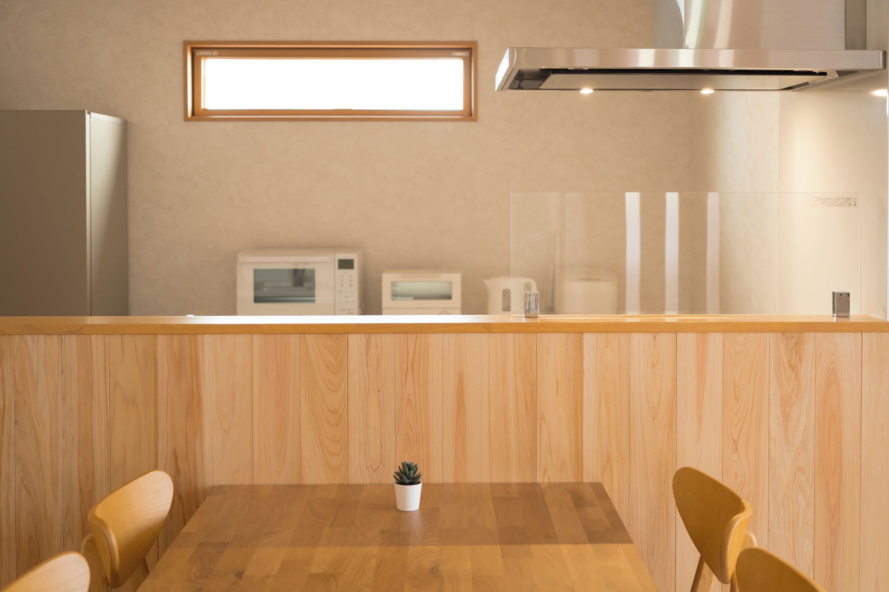 A modern kitchen with wooden cabinetry, a built-in microwave, and a stainless steel range hood.