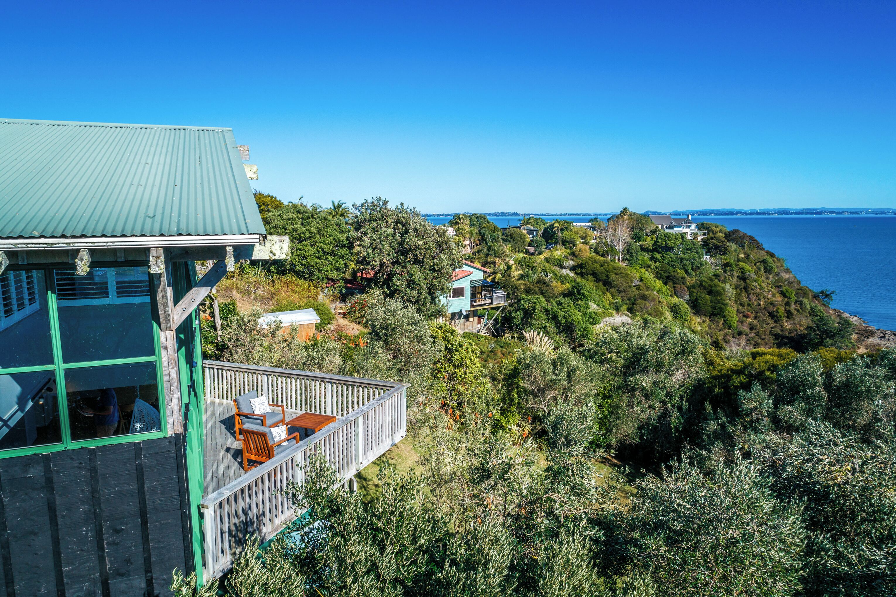 A coastal property with a wooden deck, a small house, and a view of the sea.