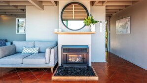 A modern living room with a fireplace, a sofa, and a coffee table. - Spinnaker Watch - Waiheke Island (Waiheke Island)