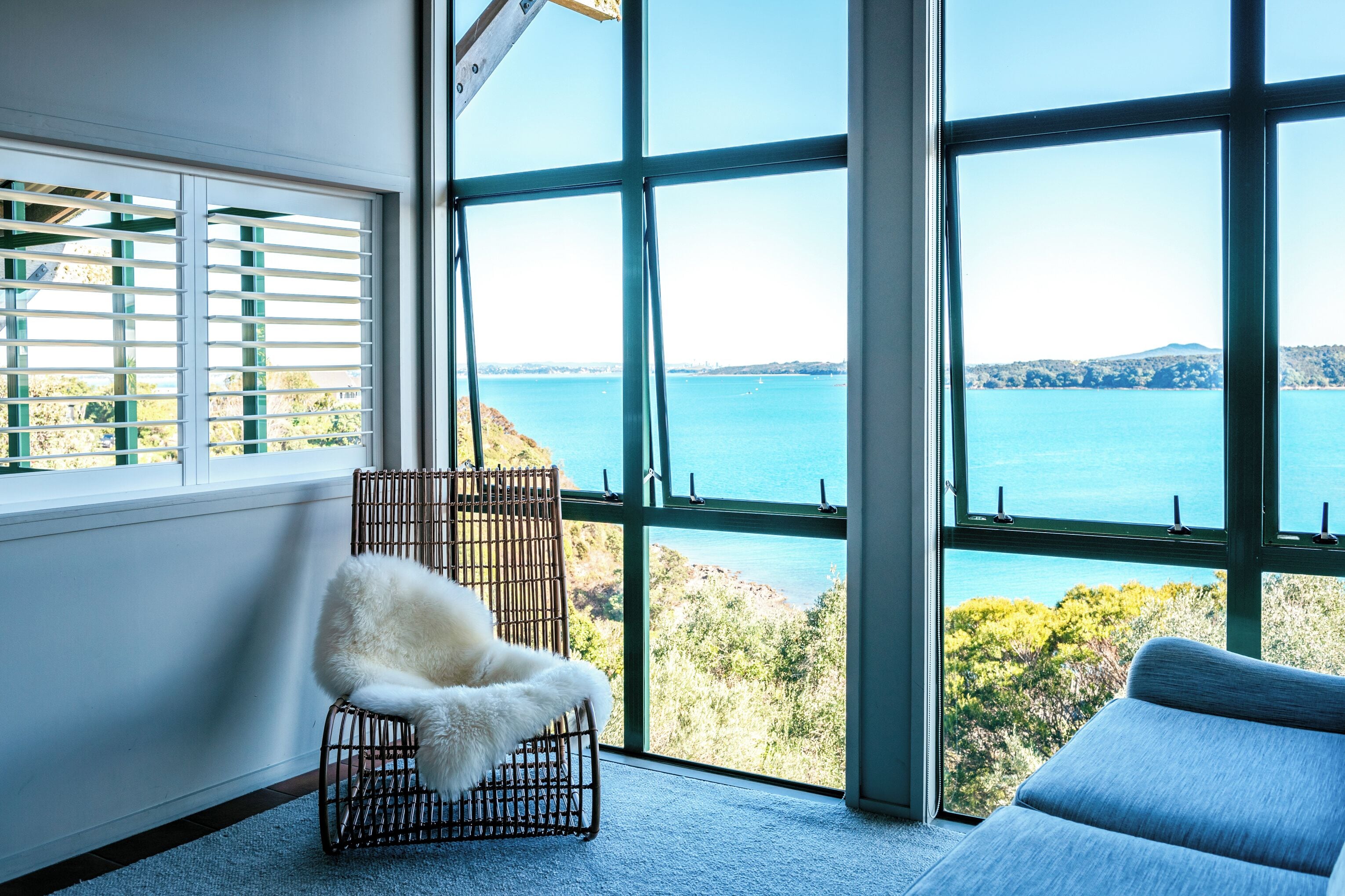 A room with large windows offering a view of a body of water and greenery.