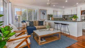 A modern living room with a sofa, coffee table, and a dining area with bar stools.