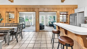A modern kitchen with wooden accents, a dining area with a table and chairs, and a bar area with stools.