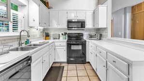 A modern kitchen with white cabinets, a stainless steel sink, a microwave, a stove, and a toaster.