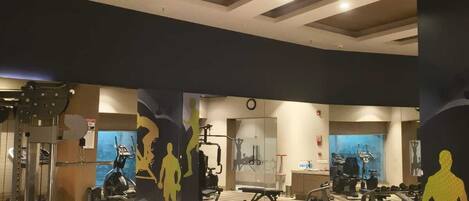 A gym with various exercise equipment, including dumbbells, a bench, and weight machines.