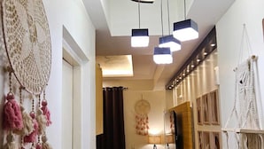 A hallway with a wooden floor, a mirror, a desk with a computer, and macramé wall hangings. - Homeiihood Stay Lucknow (Lucknow)
