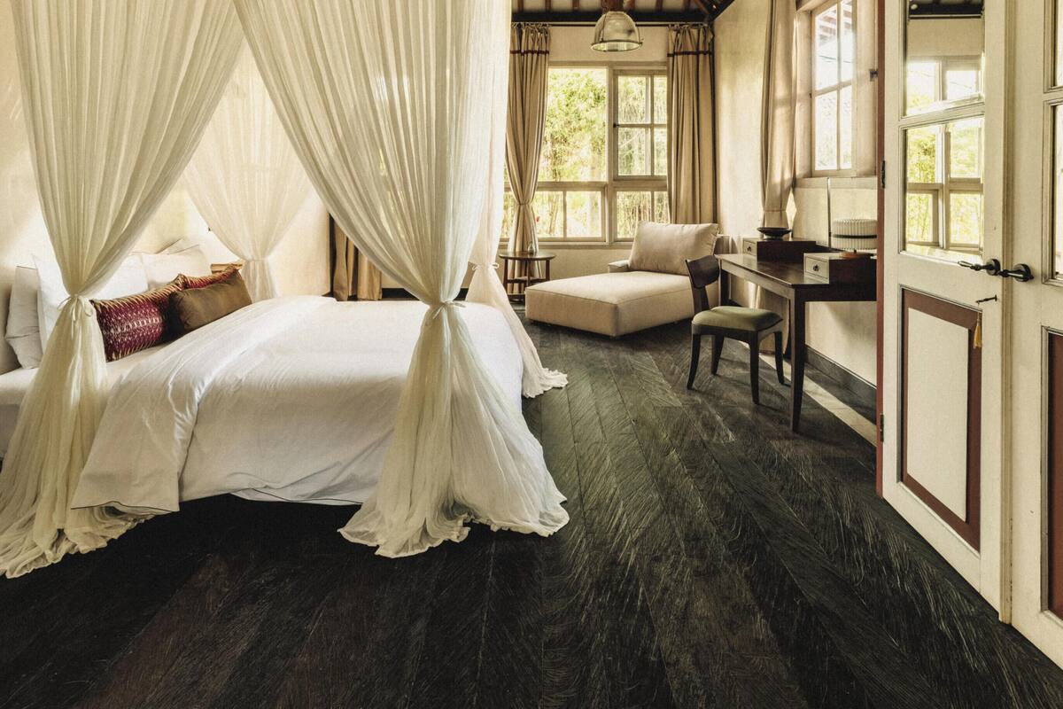 A bedroom with a canopy bed, a desk, and a chair.