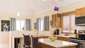 Una cocina moderna con una isla central, taburetes de bar, un microondas y una estufa.