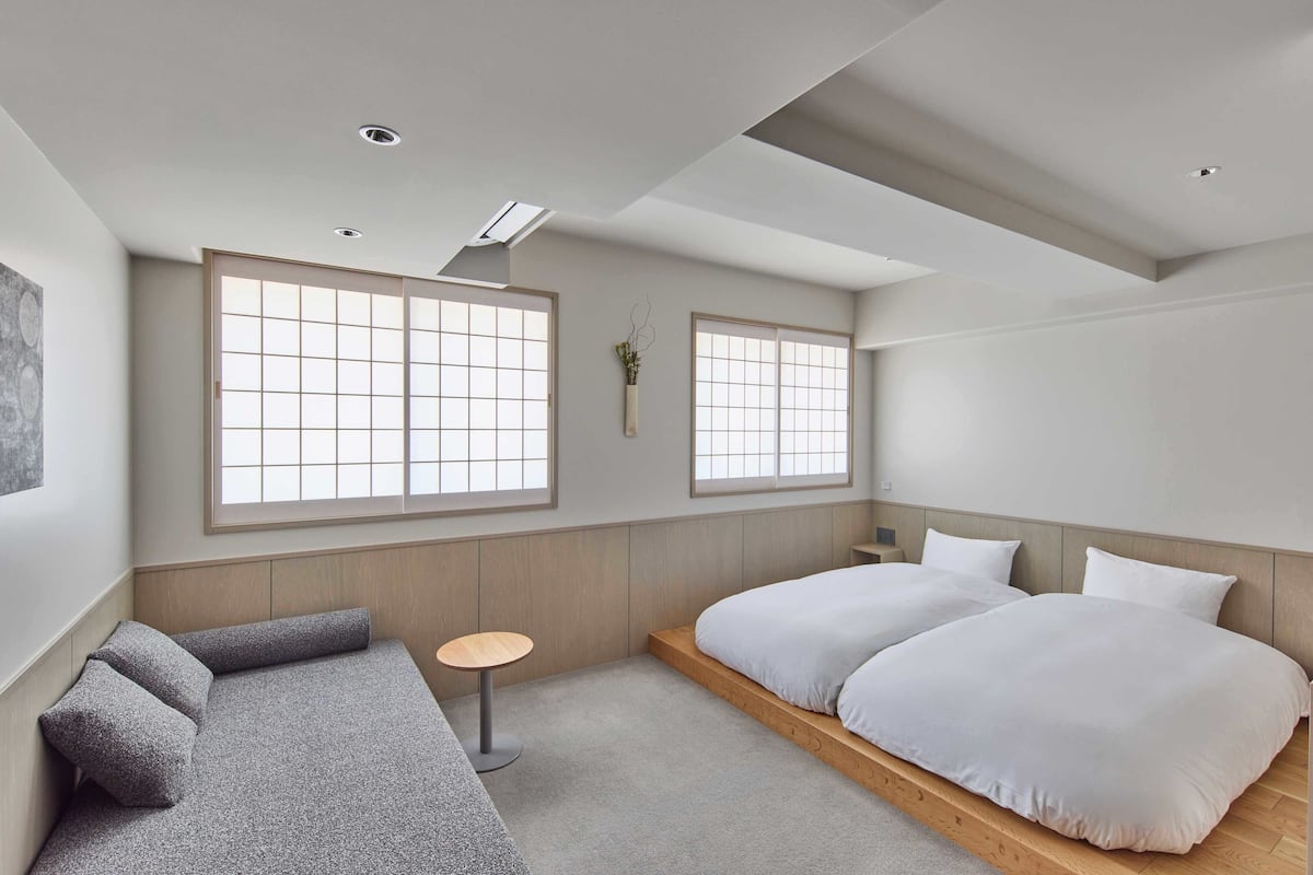 Ein modernes Schlafzimmer mit einem Bett, einer Couch, einem kleinen Tisch und großen Fenstern.
