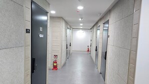 A long, narrow hallway with doors on both sides, a fire extinguisher, and a fire alarm on the wall. - BonghwangINN BonghwangMansion2 (Gyeongju)