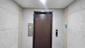 An elevator in a hallway with a textured wall, a tactile paving strip, and a control panel. - BonghwangINN BonghwangMansion2 (Gyeongju)