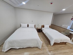 A hotel room with two single beds, a small table, a chair, and a bedside table with a lamp. - BonghwangINN BonghwangMansion2 (Gyeongju)