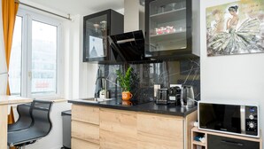 A modern kitchen with black cabinets, a marble countertop, a coffee maker, and a microwave. - Chic Parisian Apartment - Air-Con, 1-Bed (Le Kremlin-Bicetre)