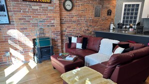 A cozy living area with a brick wall, a leather sofa, a wooden coffee table, and a fireplace. - Urban Escape Modern Condo in the Heart of It All (Columbus)