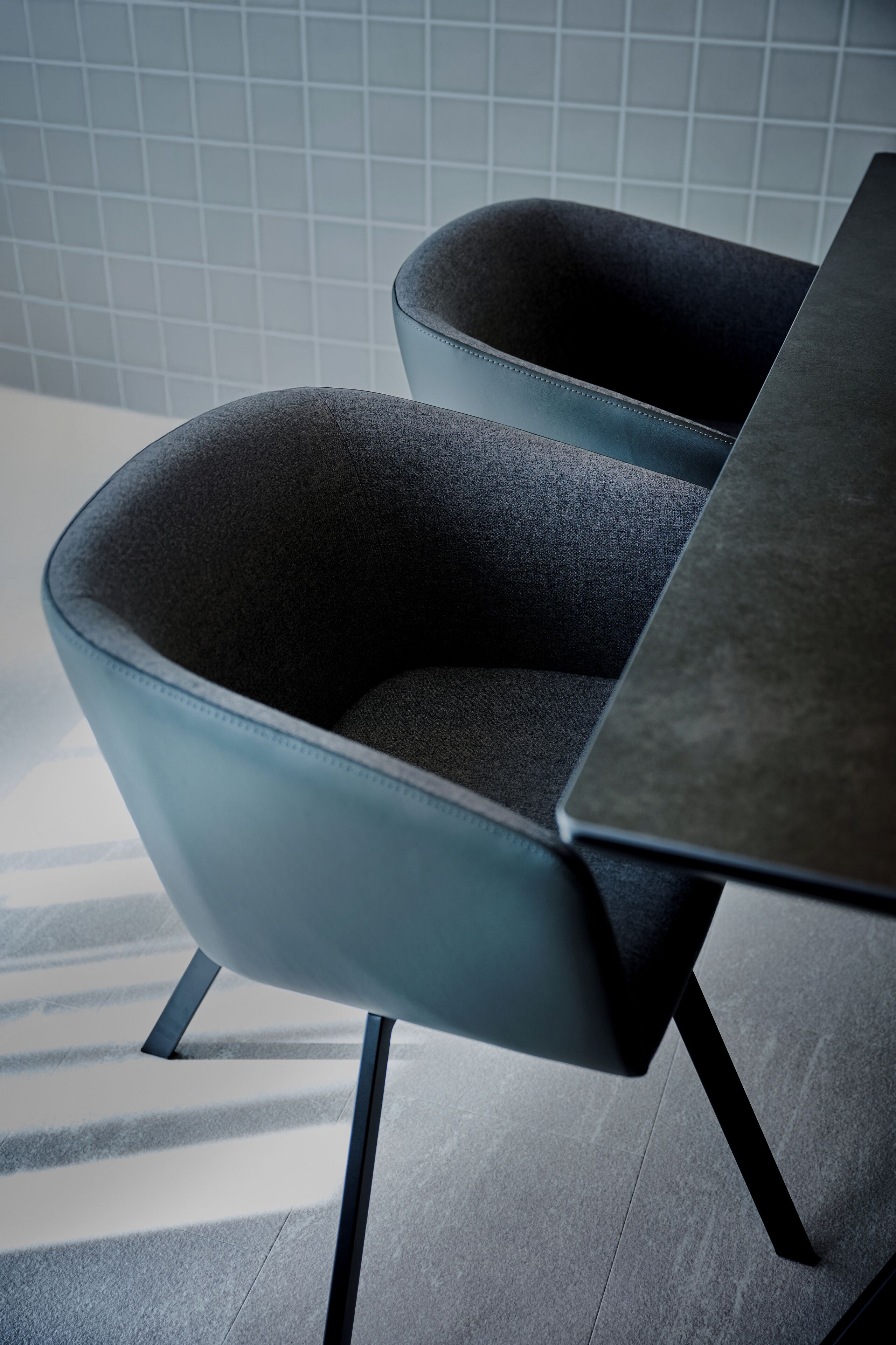 A modern chair with a dark fabric seat and backrest, paired with a sleek, dark table.