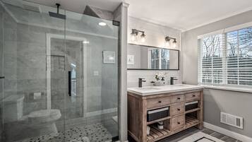 Une salle de bain moderne avec une douche à parois de verre, un meuble-lavabo en bois et un grand miroir.