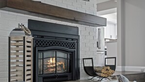 A fireplace with a log basket and a metal lantern beside it.