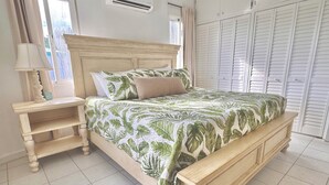 A bedroom with a bed, a nightstand, a wardrobe, and a window.