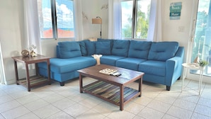 A living room with a blue sectional sofa, a wooden coffee table, and a small side table.