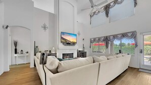 Un salon moderne doté d’un grand canapé, d’un téléviseur à écran plat, d’une cheminée et d’un ventilateur de plafond.