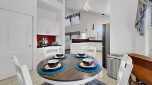 Une cuisine moderne avec des meubles blancs, une table à manger agrémentée de sets de table bleus et un four encastré.