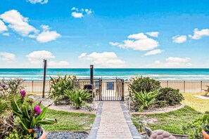 A pathway leading to a beach with a gate, surrounded by tropical plants and a clear view of the ocean. - NEW! Escape `Two` Oceanside - Updated Double Studio w/ Pool & Beach Access (Daytona Beach)