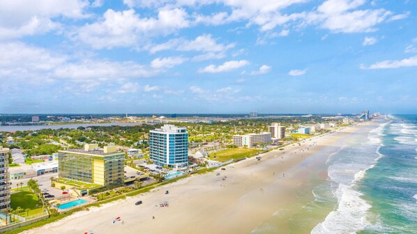 A coastal cityscape with a beachfront hotel, a pool, and a view of the ocean. - NEW! Escape `Two` Oceanside - Updated Double Studio w/ Pool & Beach Access (Daytona Beach)