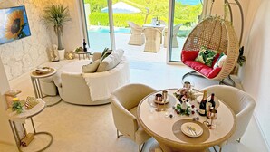 A modern living room with a round table set for a meal, a hanging chair, and a sofa. - Resort Villa KAPUKA SESOKOJIMA (Motobu)