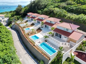 Um empreendimento costeiro com várias villas, cada uma com piscina e vista para o mar.