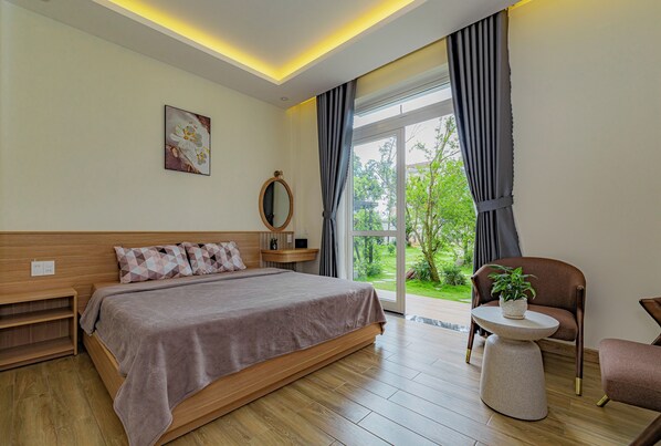 Un dormitorio moderno con una cama grande, una mesita de noche, una silla y vistas a zonas verdes.