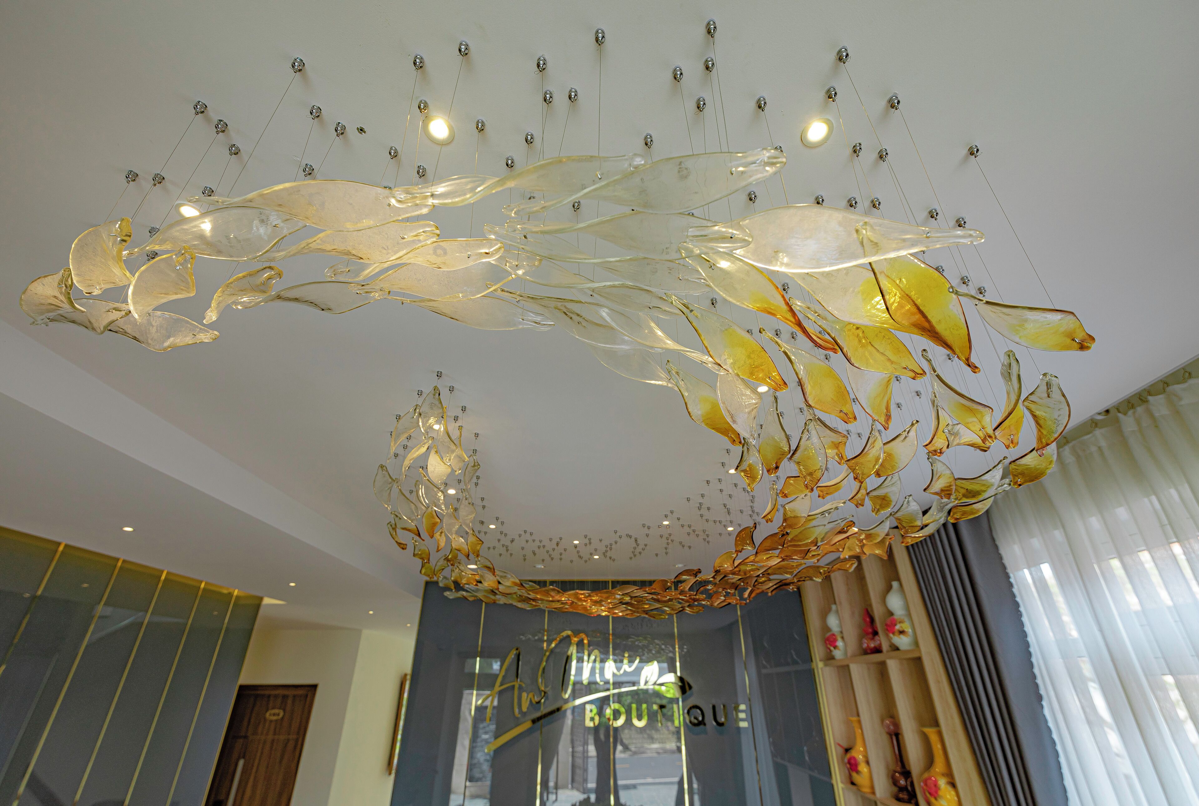 Un intérieur moderne agrémenté d’un lustre en verre original et d’une enseigne de boutique.