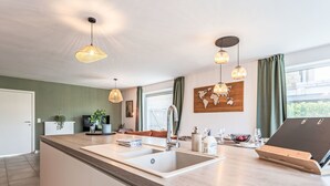 Eine moderne Küche mit einer zentralen Kochinsel, Pendelleuchten und einer Weltkarte als Wandbild.