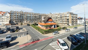 Een modern appartementencomplex met een traditioneel huis op de voorgrond.