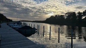 Un rivage paisible, avec des bateaux amarrés, une jetée en bois et un coucher de soleil sur une rivière.