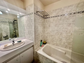 A bathroom with a sink, mirror, shower, and bathtub.