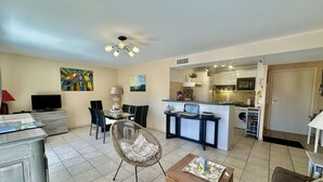 A living room with a TV, dining area, kitchen, and a ceiling fan.