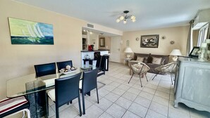 A dining area with a glass table and chairs, a sofa, and a decorative cabinet.