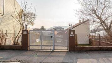 A gated entrance with a metal gate, a building with a beige facade, and a number '122' sign.