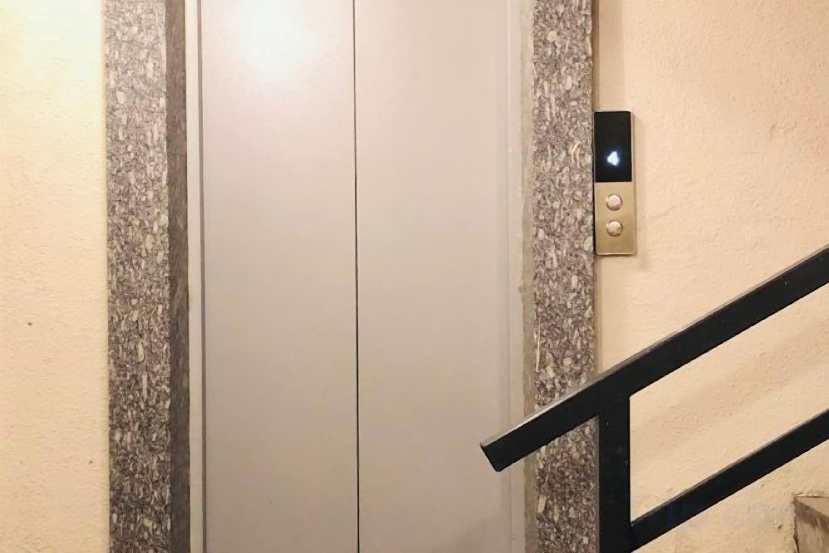 A closed elevator door with a wall-mounted control panel.