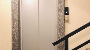 A closed elevator door with a wall-mounted control panel.
