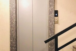 Puerta cerrada de un ascensor con un panel de control en la pared.
