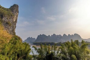A natural landscape with a river, a cliff, and a series of mountains in the background. - Gongxingshe·Xichishanju homestay (Xingping Branch, Yangshuo) (Yangshuo)