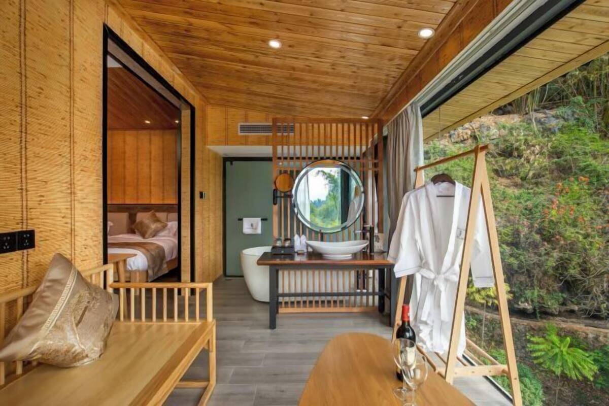 A wooden interior with a bench, a sink, and a hanging robe rack.