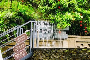 Una cascada fluye sobre una estructura de piedra con una escalera metálica que asciende hacia ella.