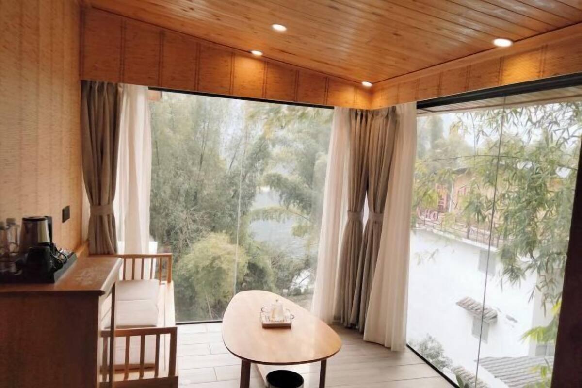 A room with a wooden ceiling, a table with a cup, and a chair.