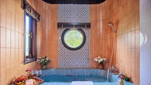 Ein Badezimmer mit einer Badewanne, einem Fenster und einer Dusche.