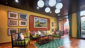 Eine gemütliche Lobby mit Holzboden, gerahmten Kunstwerken an den Wänden, einem Teppich mit grünem Muster und einer Sitzecke mit gepolsterten Stühlen und einem kleinen Tisch.